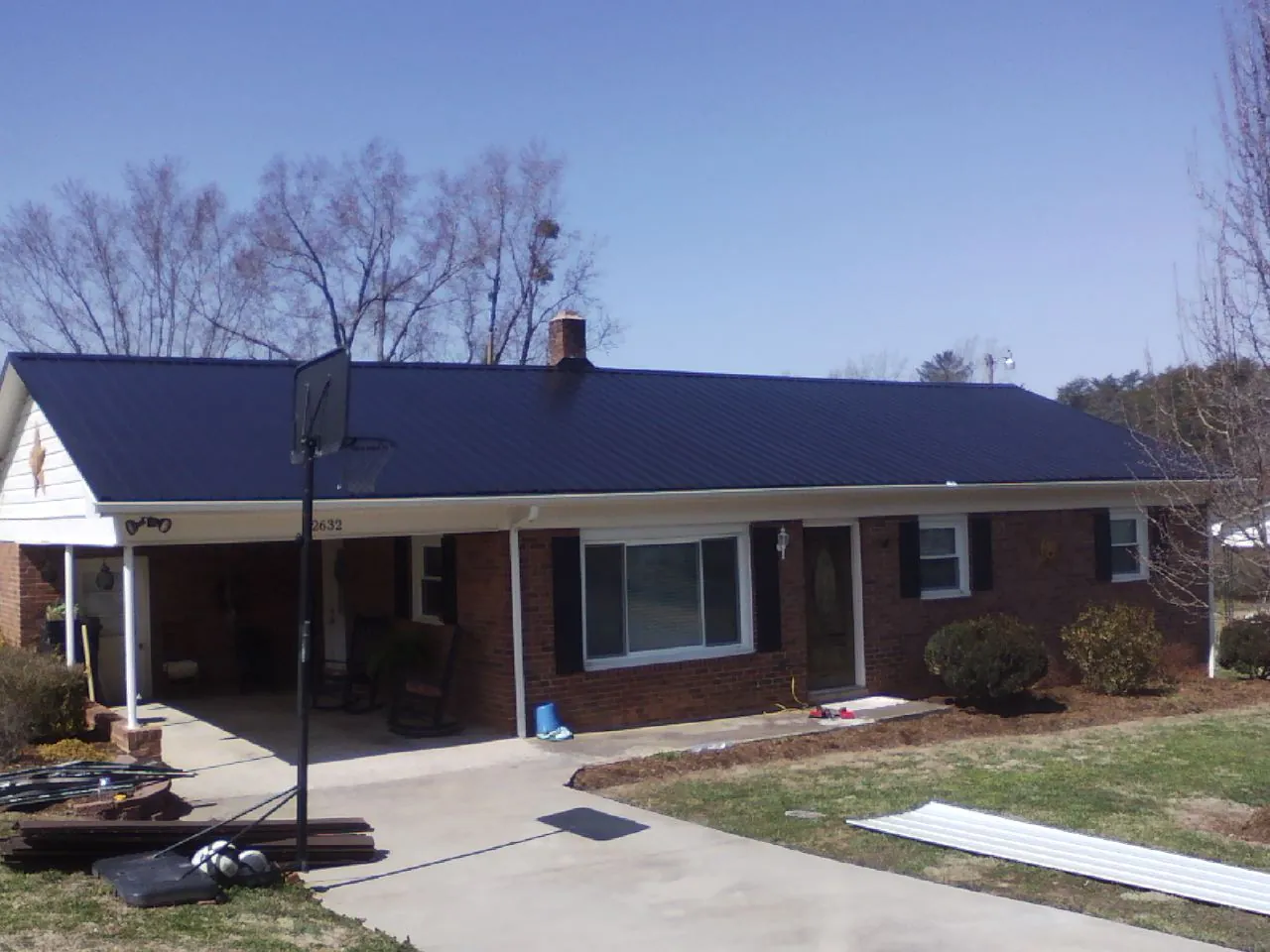 Finished dark blue metal roof on a brick ranch with a carport in Millbury