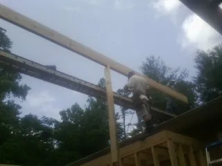 Carpenter setting a ridge beam over a new addition frame — Ice Dam Removal by Roofing Brothers in Millbury