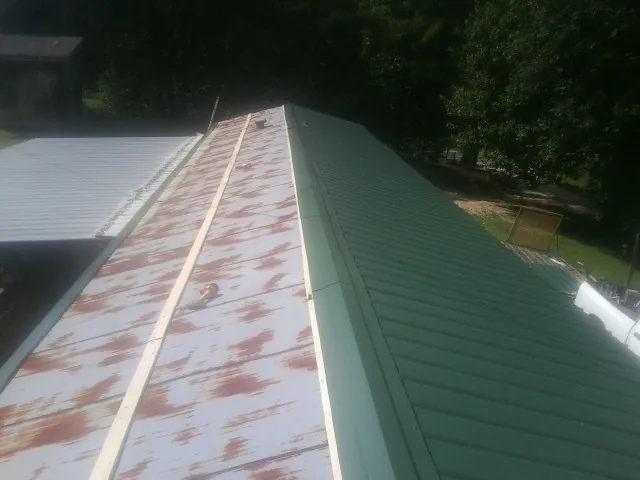 Old rusted panels beside newly installed green metal roofing — Wind Damage Roof Repair by Roofing Brothers in Millbury