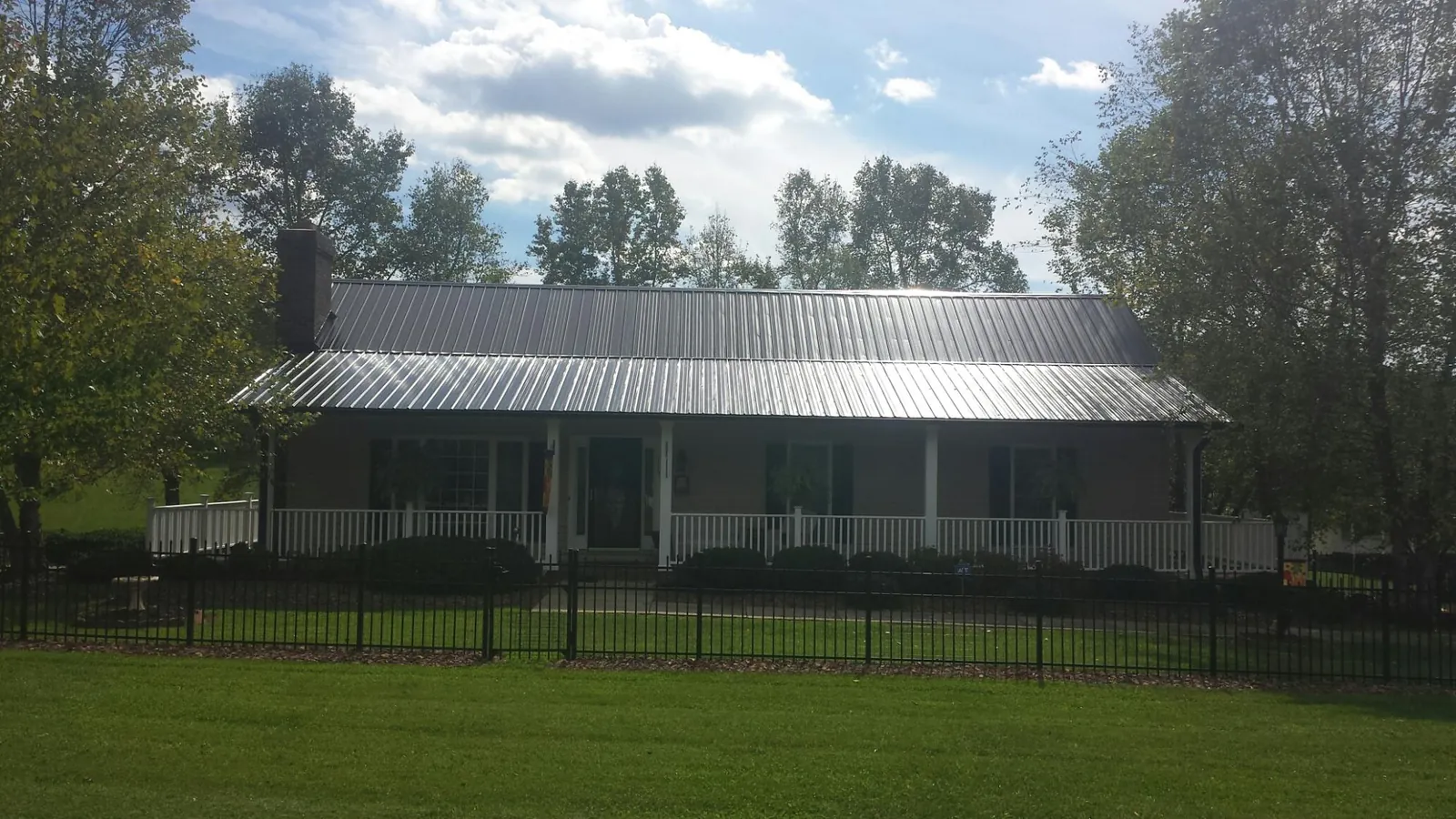 Gray metal roof on a brick ranch with a full width front porch — Gutter Guard Installation work by our crew in Millbury